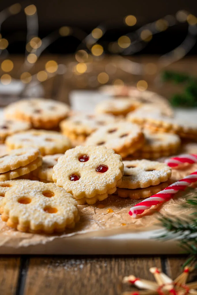 Linzer Kekse in weihnachtlichem Setting mit Zuckerstange und Lichterkette.