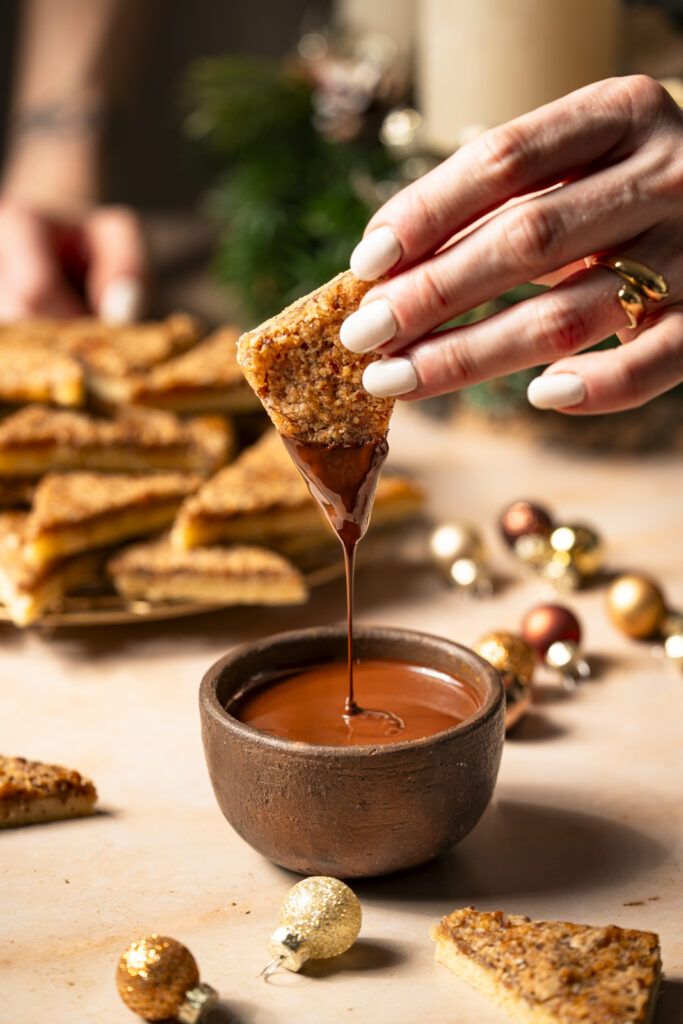 Die Spitzen von Nussecken werden in geschmolzene Schokolade getunkt.