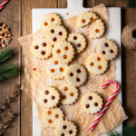 Linzer Augen gefüllt mit Marillenkonfitüre und Ribiselkonfitüre, arrangiert auf Backpapier und einem Marmorbrett.