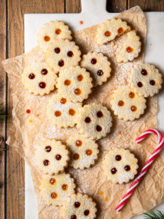 Linzer Augen gef&uuml;llt mit Marillenkonfit&uuml;re und Ribiselkonfit&uuml;re, arrangiert auf Backpapier und einem Marmorbrett.