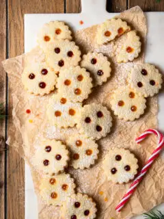 Linzer Augen gefüllt mit Marillenkonfitüre und Ribiselkonfitüre, arrangiert auf Backpapier und einem Marmorbrett.
