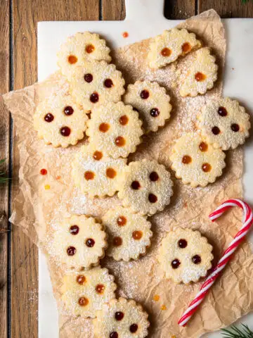 Linzer Augen gef&uuml;llt mit Marillenkonfit&uuml;re und Ribiselkonfit&uuml;re, arrangiert auf Backpapier und einem Marmorbrett.
