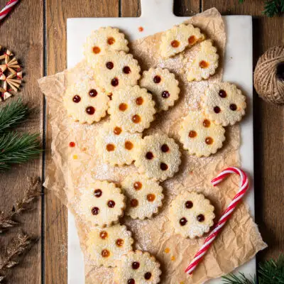 Linzer Augen gef&uuml;llt mit Marillenkonfit&uuml;re und Ribiselkonfit&uuml;re, arrangiert auf Backpapier und einem Marmorbrett.