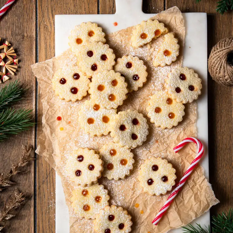 Linzer Augen gef&uuml;llt mit Marillenkonfit&uuml;re und Ribiselkonfit&uuml;re, arrangiert auf Backpapier und einem Marmorbrett.